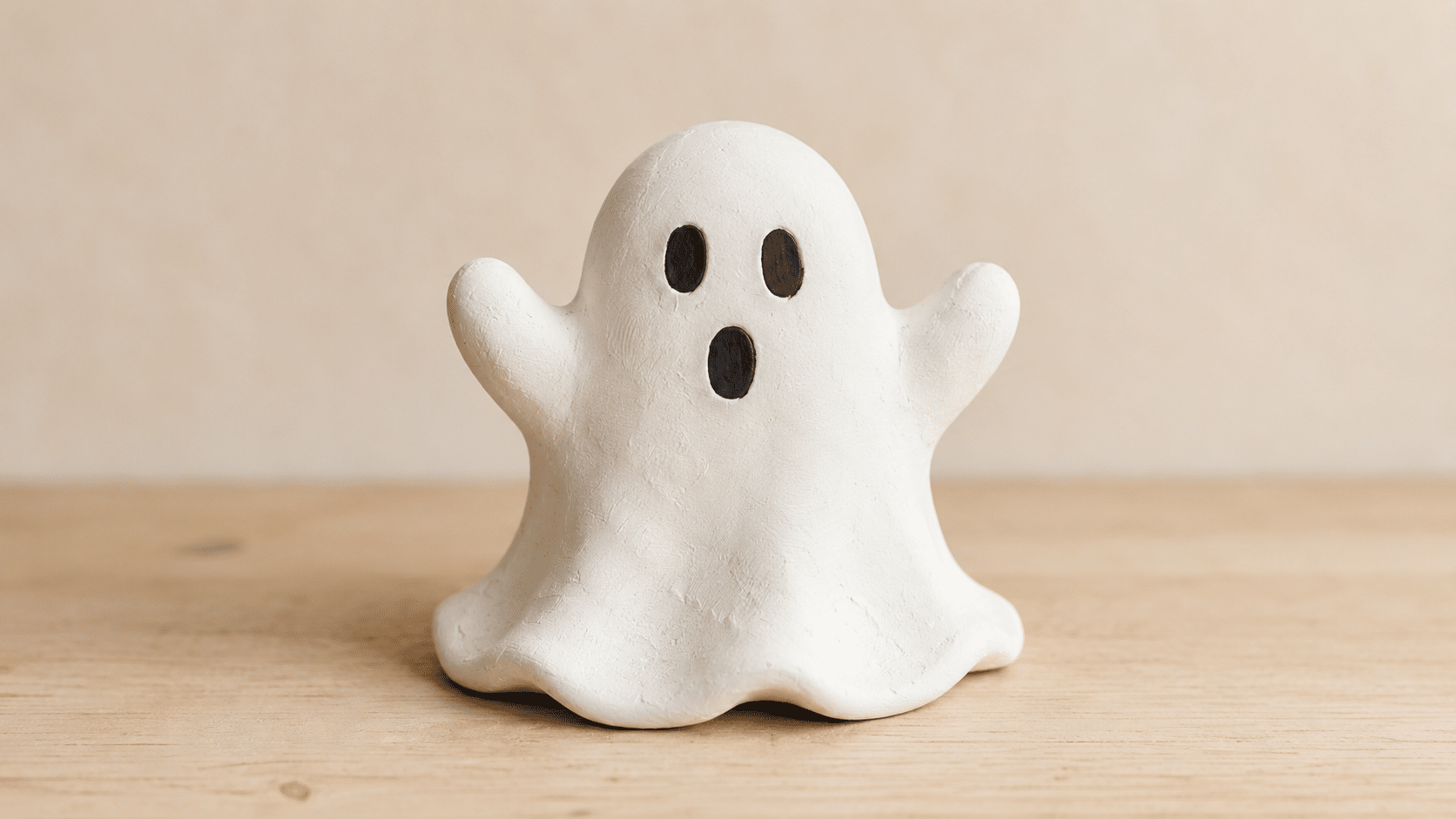 Cute white clay ghost raising its small rounded arms