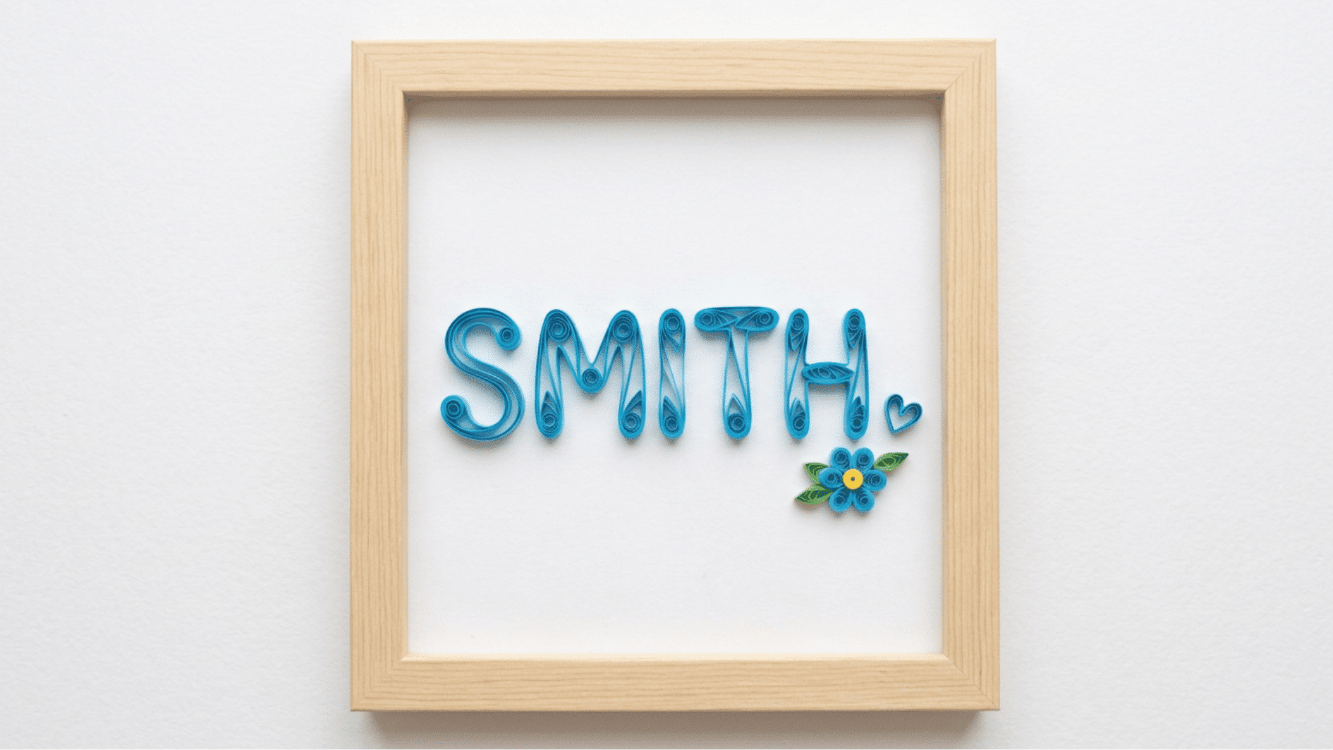 framed quilled paper name art spelling smith in blue with a small flower and heart accent