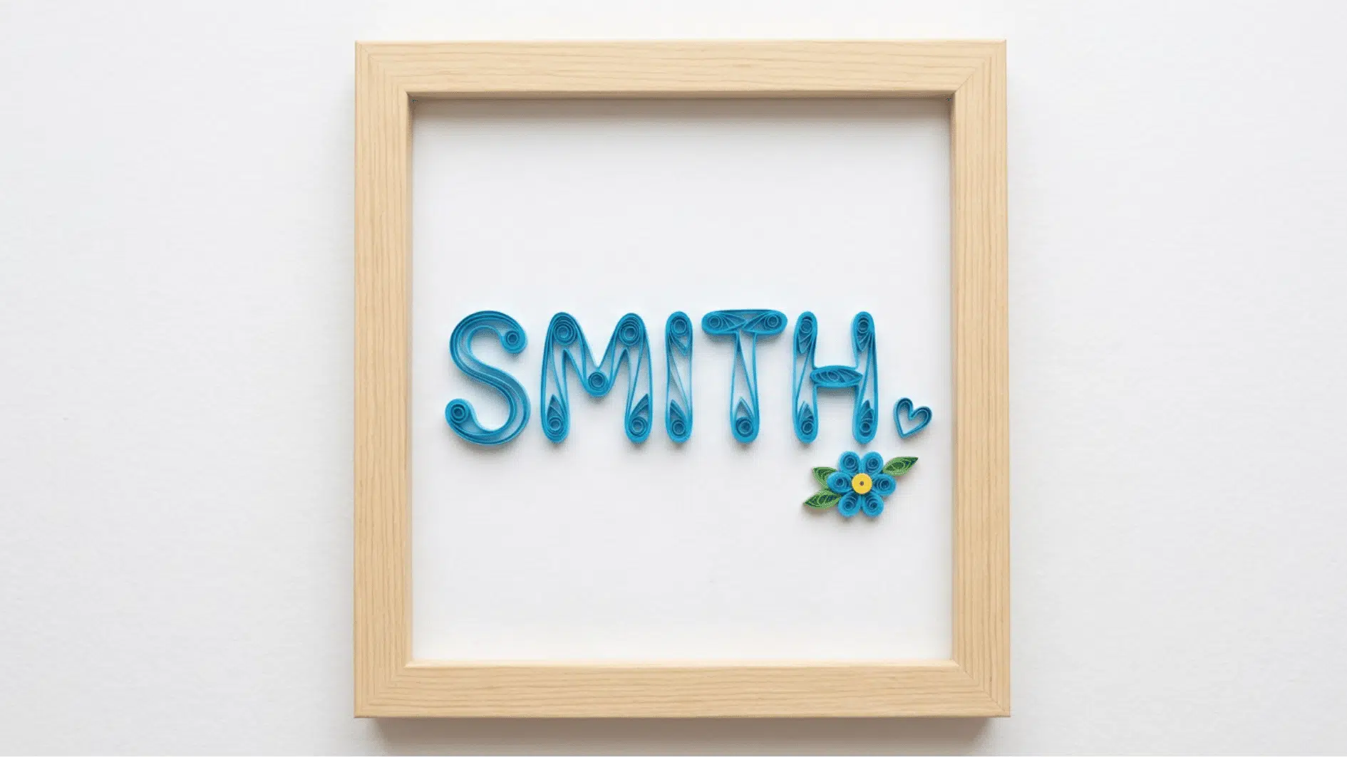 framed quilled paper name art spelling smith in blue with a small flower and heart accent