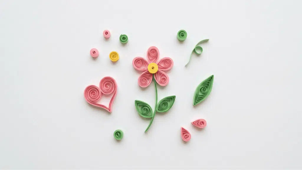 quilled paper flower heart and leaf shapes in pink green and yellow scattered on white background