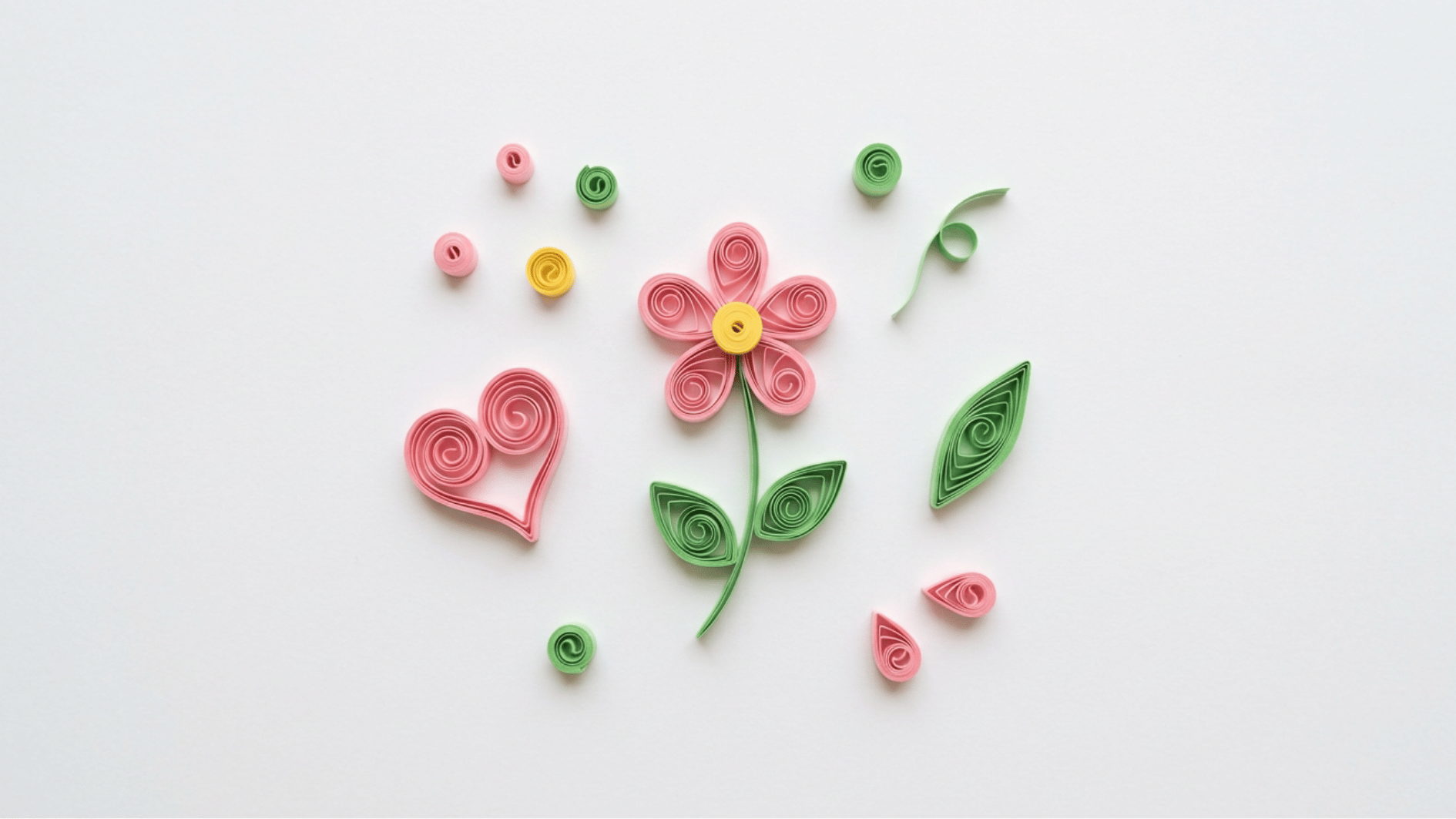 quilled paper flower heart and leaf shapes in pink green and yellow scattered on white background