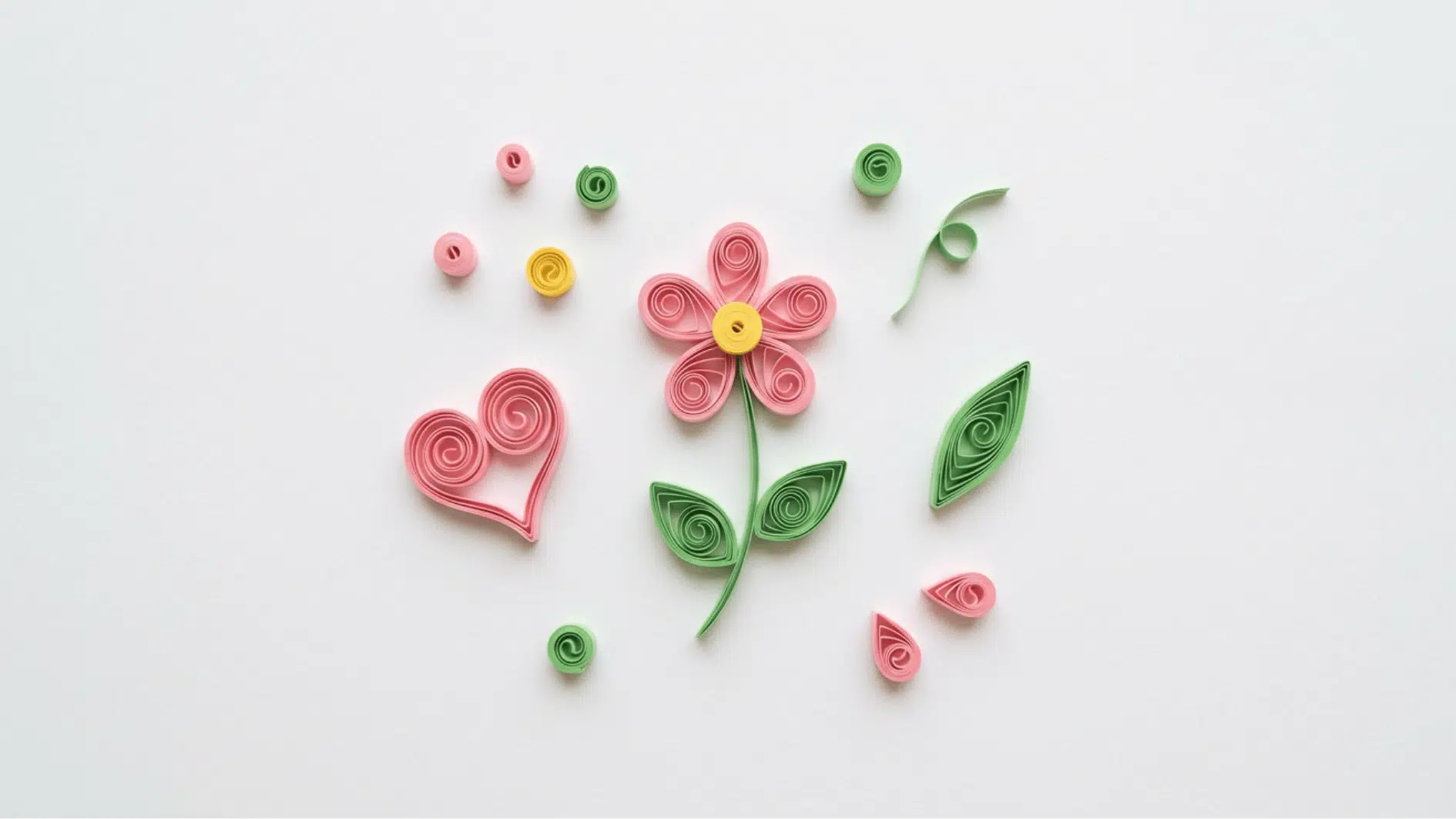 quilled paper flower heart and leaf shapes in pink green and yellow scattered on white background