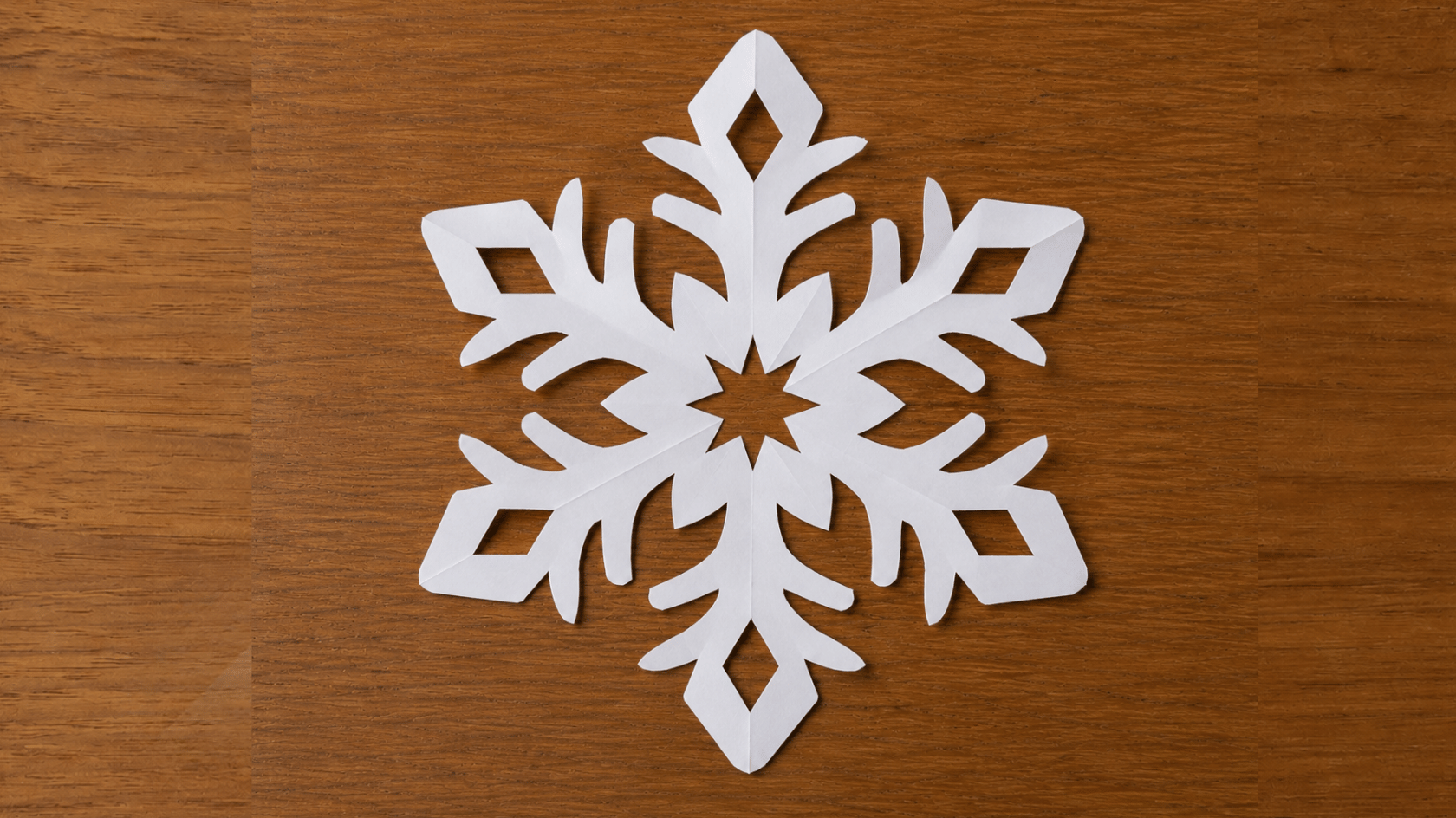 finished white six point paper snowflake on a wooden surface