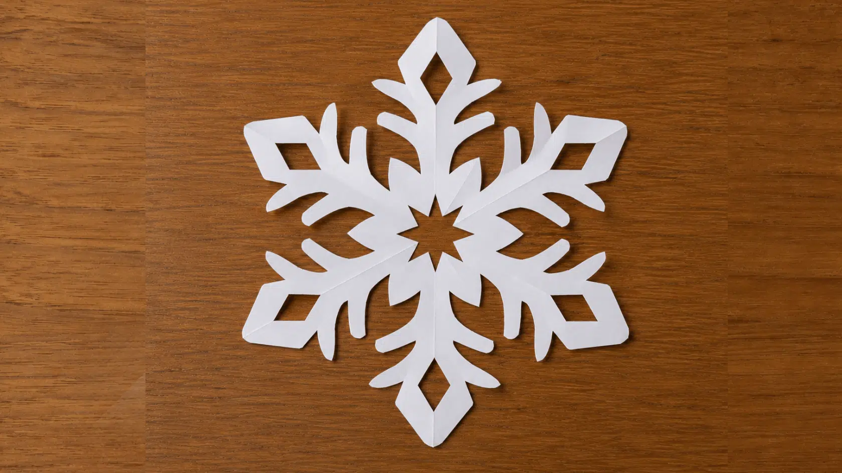 finished white six point paper snowflake on a wooden surface