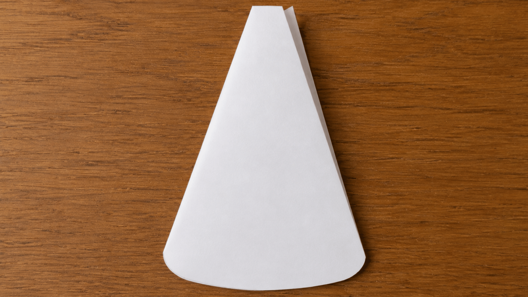 folded white paper with the top trimmed and bottom edge rounded
