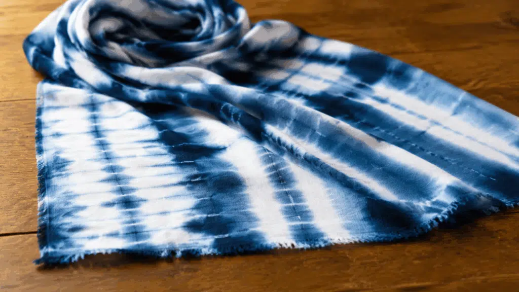 indigo shibori dyed fabric with flowing white patterns spread across a wooden tabletop surface