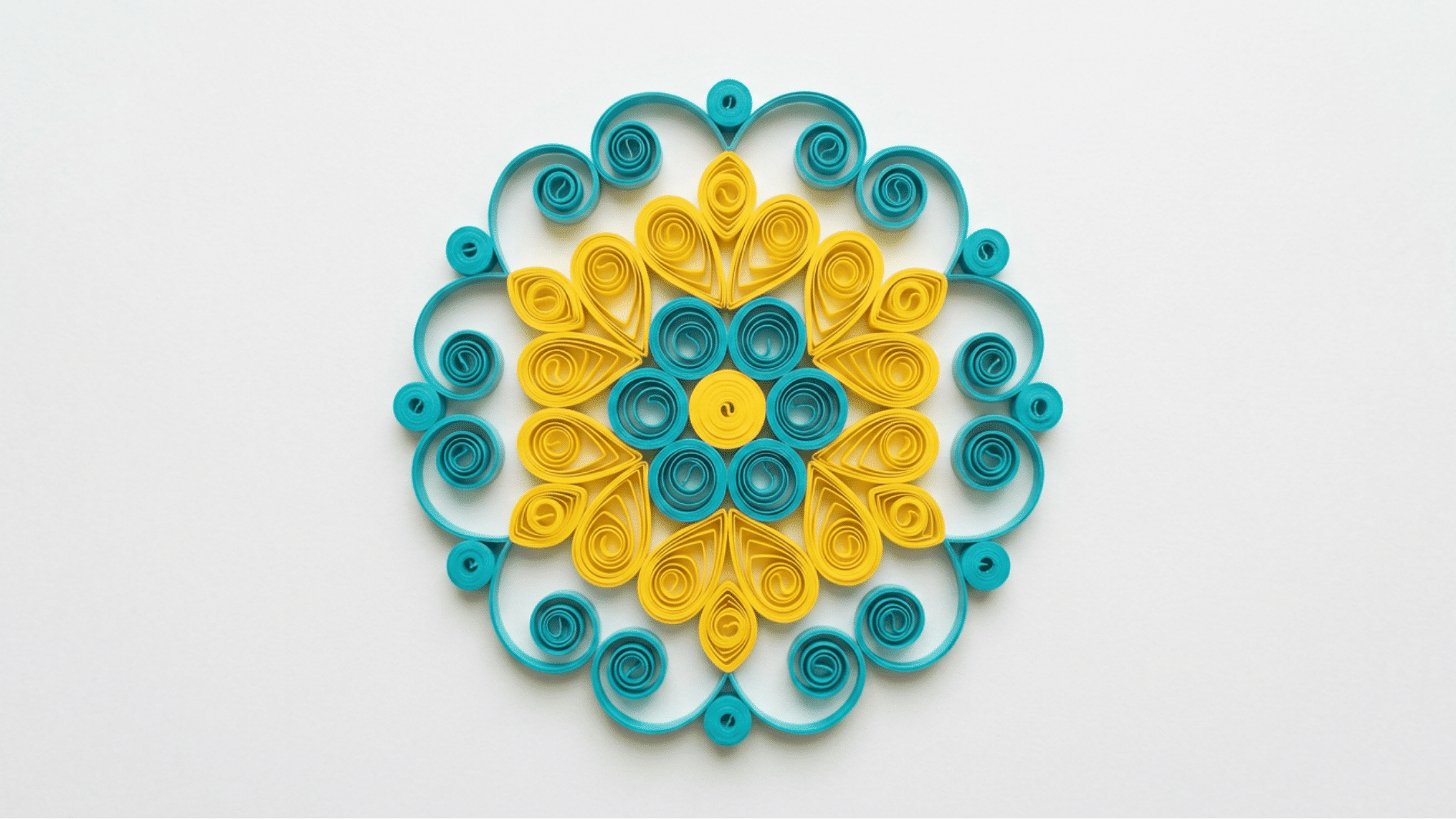 quilled paper mandala in teal and yellow with symmetrical circular pattern on white background