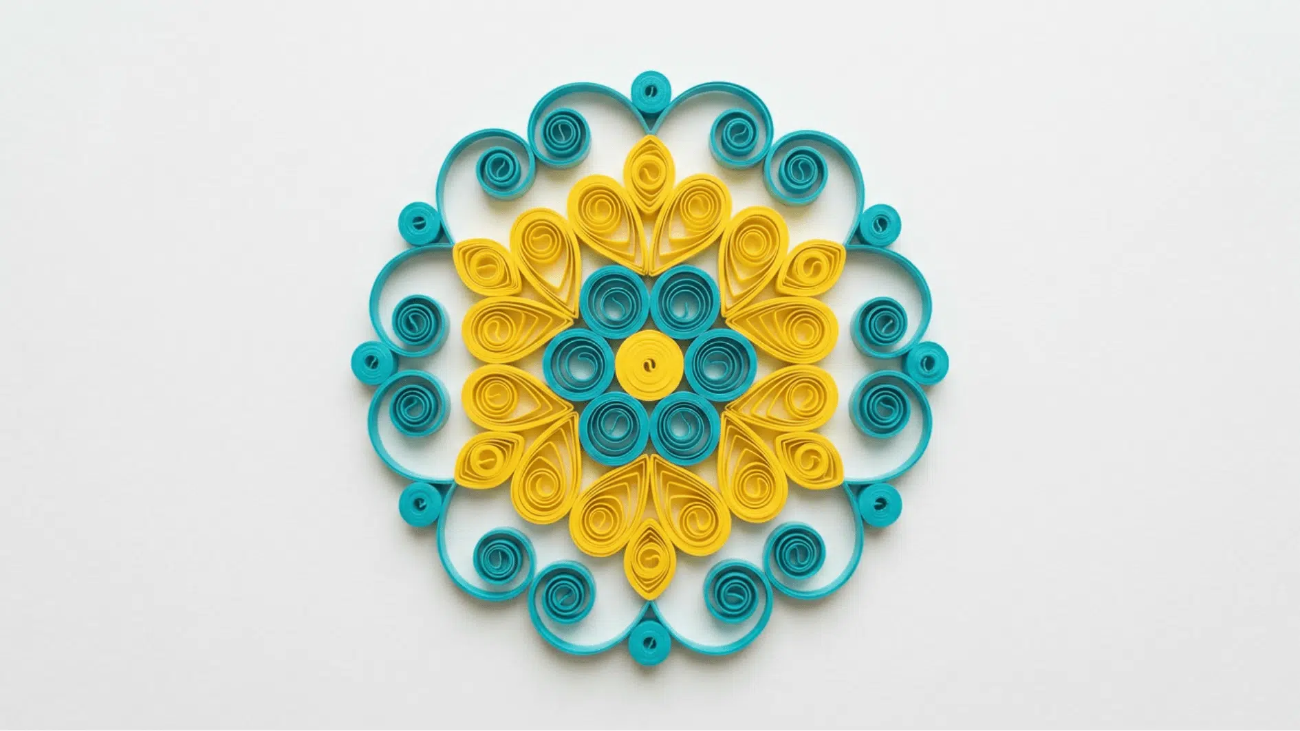 quilled paper mandala in teal and yellow with symmetrical circular pattern on white background