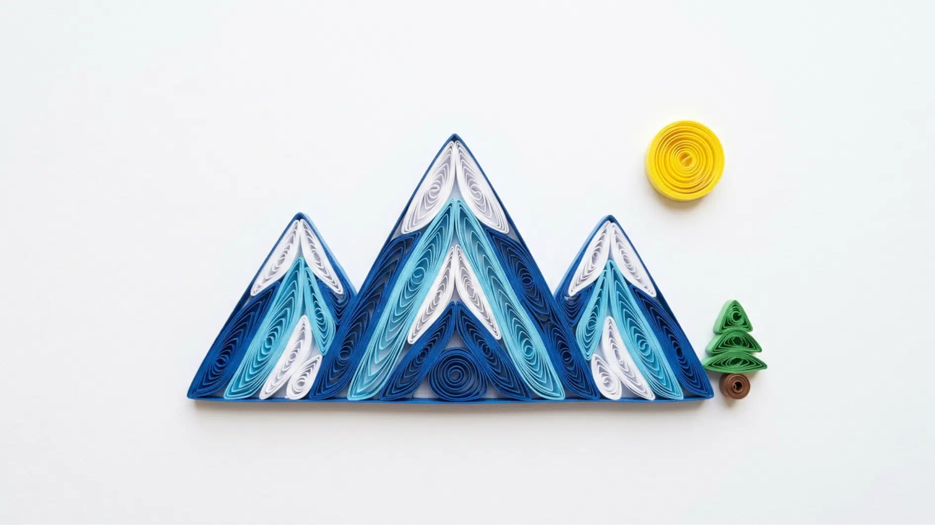 quilled paper mountain range in blue with yellow sun and green tree on white background