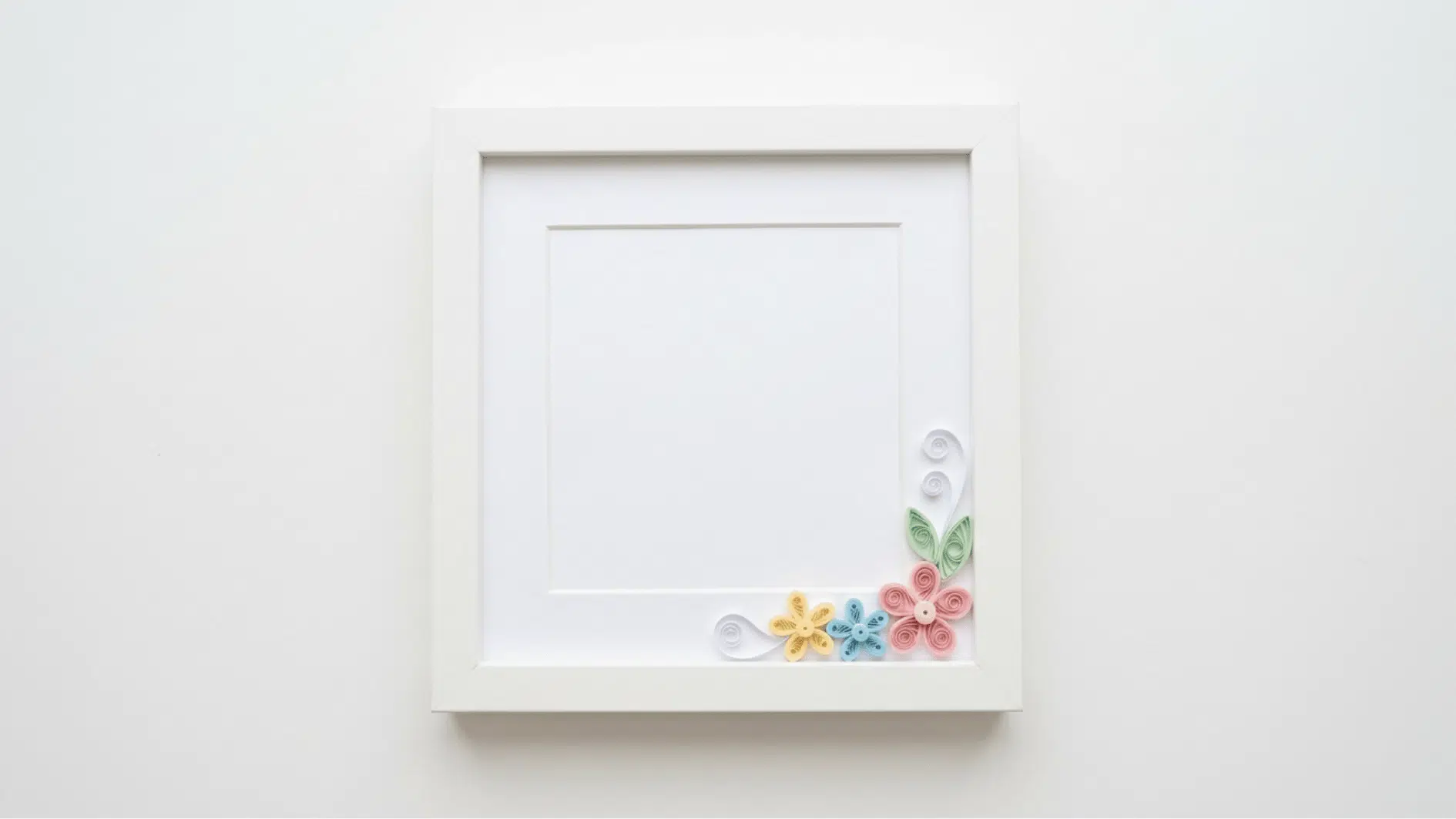 white picture frame with quilled paper flowers in yellow blue and pink in the corner