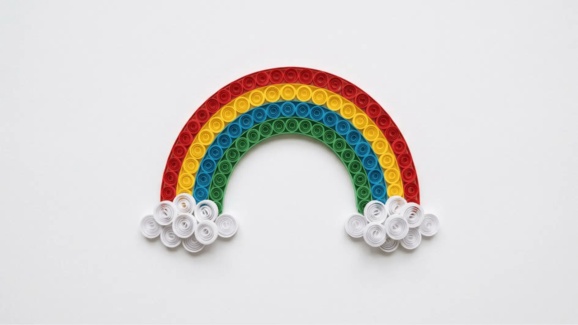 quilled paper rainbow with red yellow blue and green arcs and white cloud coils on white background