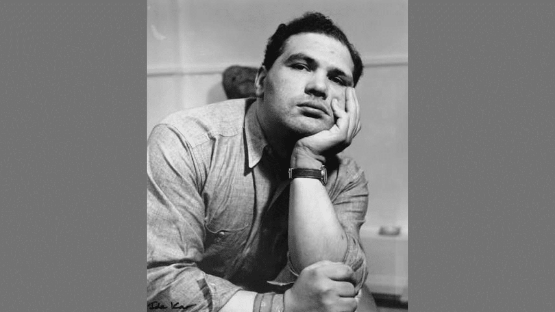 a black-and-white portrait of a man leaning his chin on his hand in a thoughtful pose
