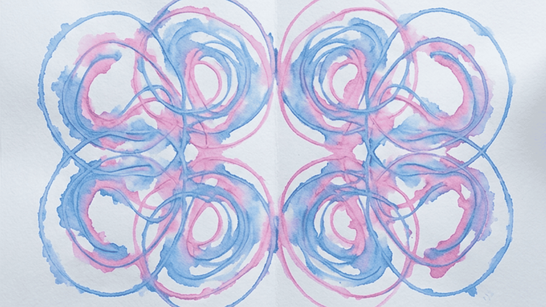 symmetrical string painting design in blue and pink swirling loops on white paper