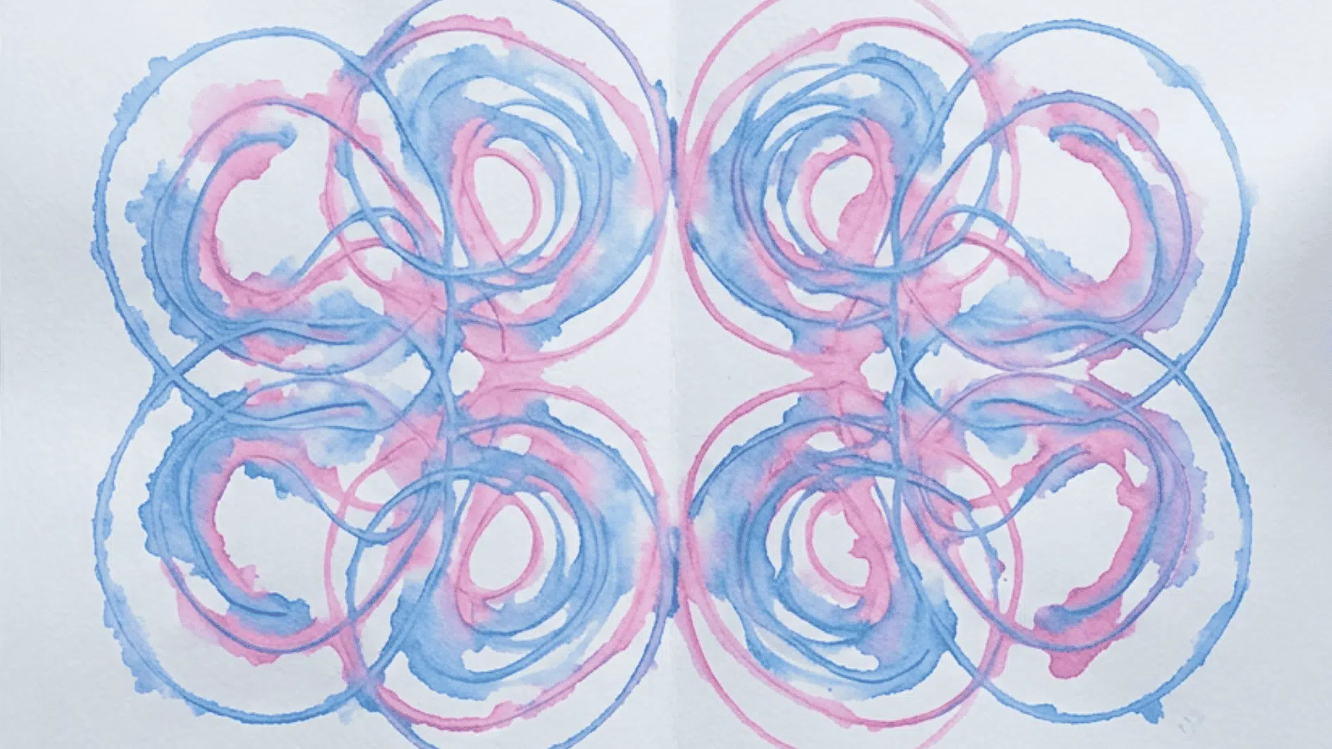 symmetrical string painting design in blue and pink swirling loops on white paper
