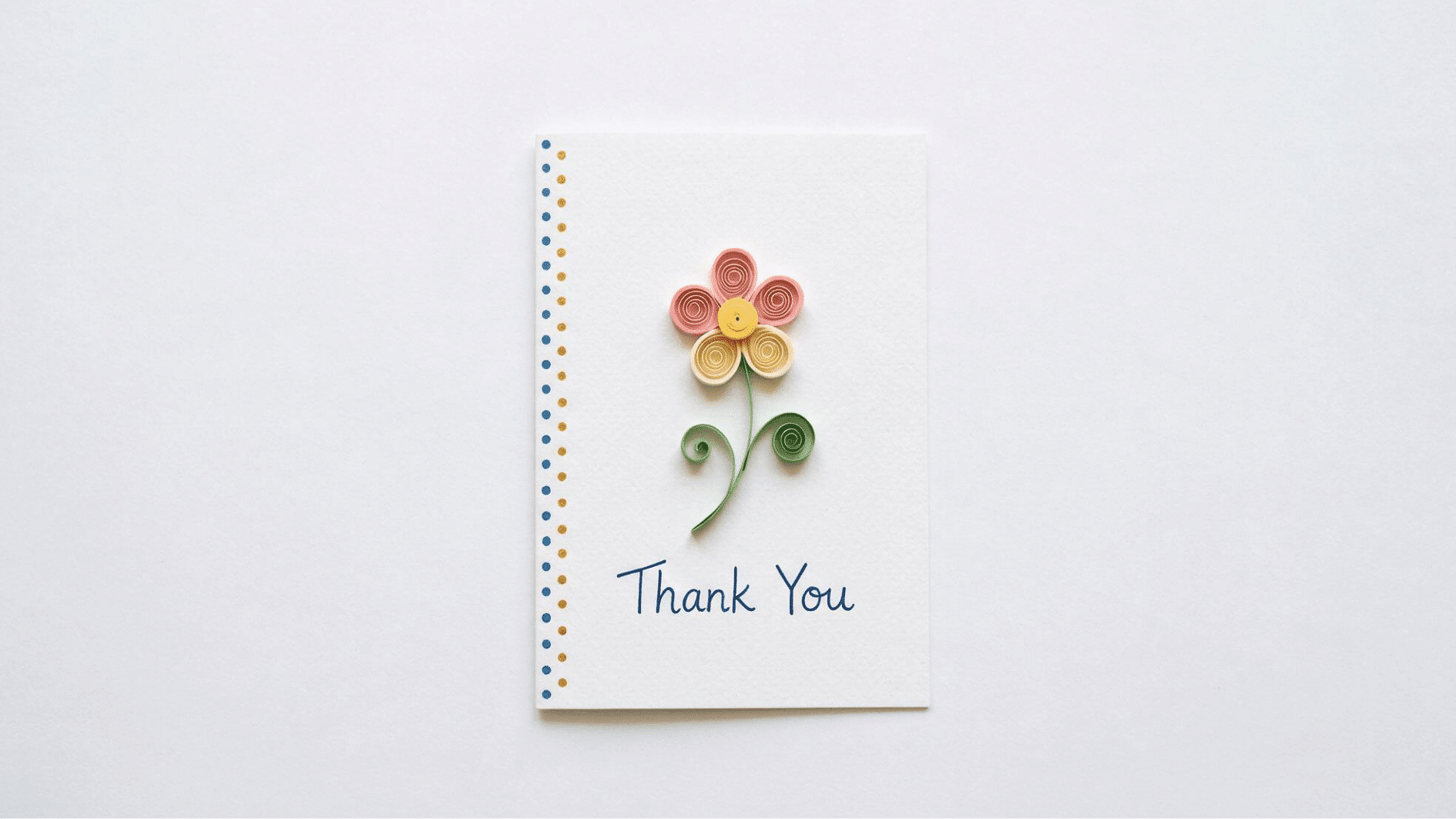 thank you card with quilled paper flower in pink and yellow with curled green stem on white background