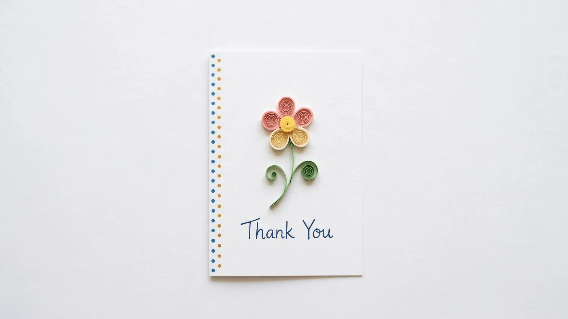 thank you card with quilled paper flower in pink and yellow with curled green stem on white background