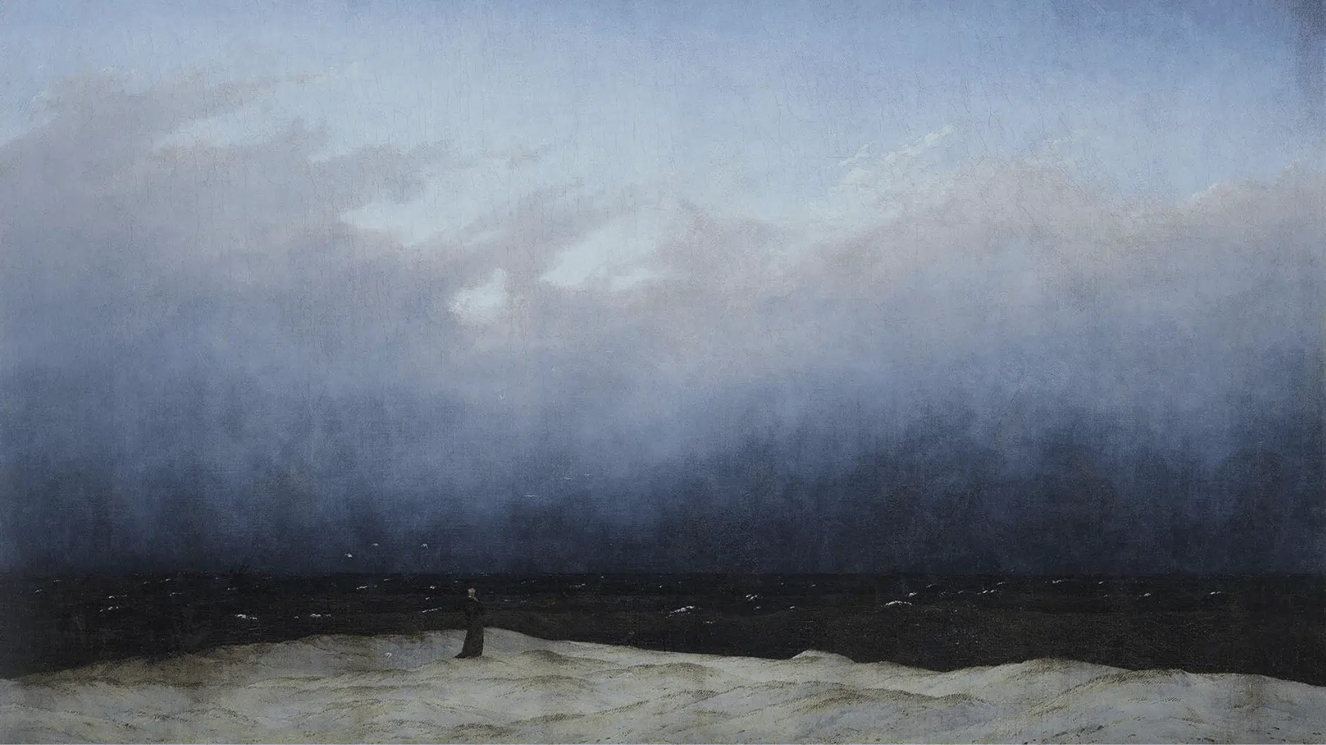 a tiny lone figure in dark robes stands on a vast empty beach beneath an immense hazy sky and dark sea