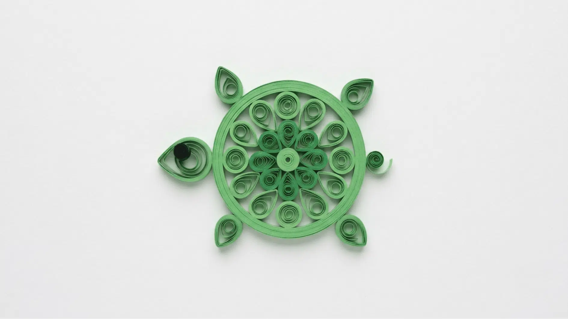 quilled paper turtle in green with a floral patterned shell on white background