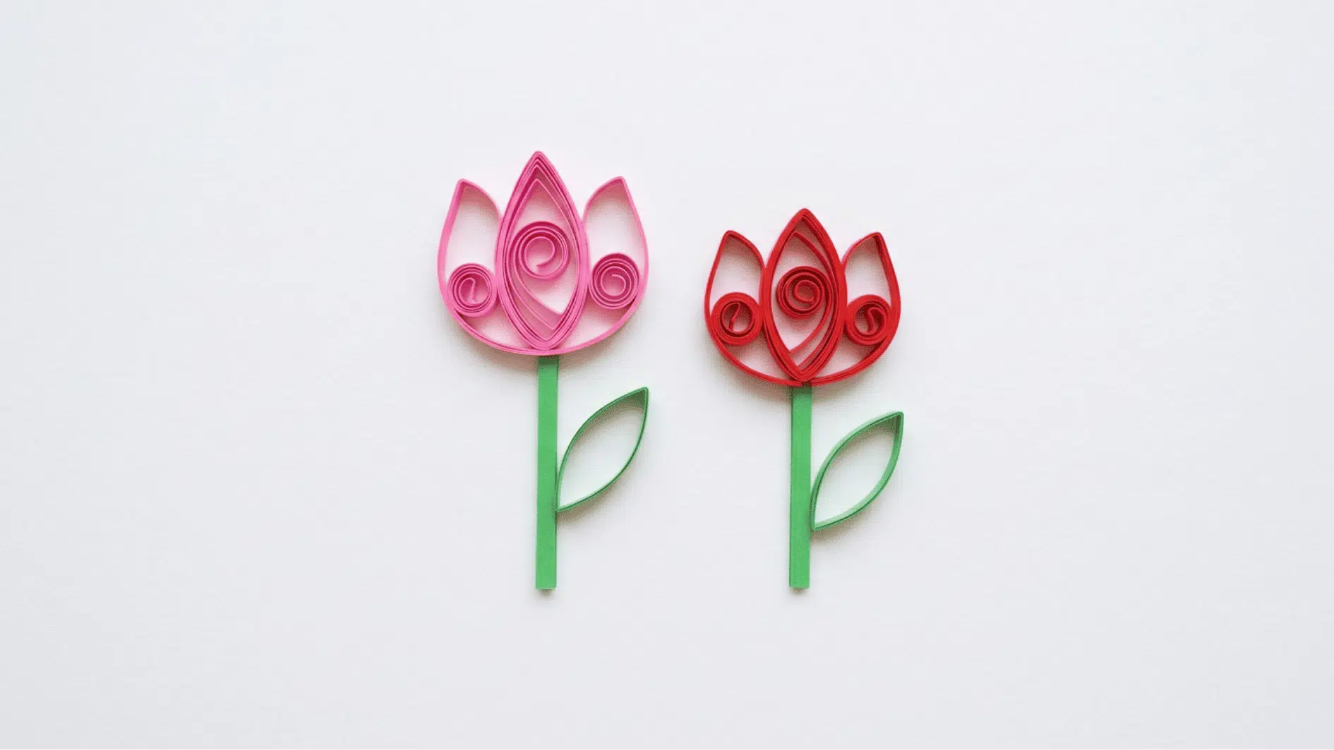 quilled paper tulips in pink and red with green stems and leaves on white background